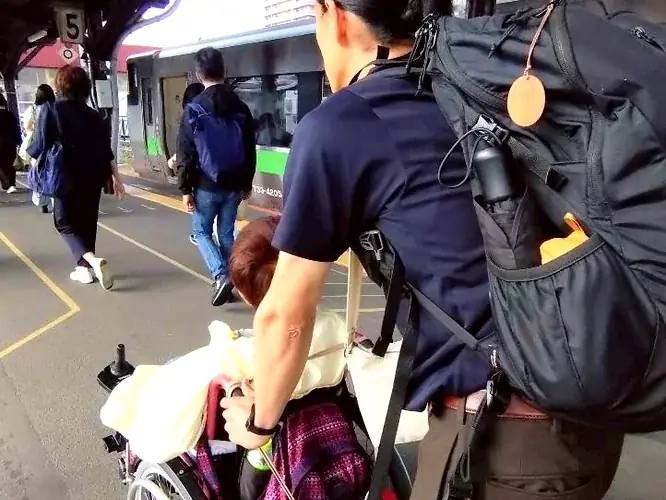 駅のホームで車椅子を押して同行するリハビリ専門職